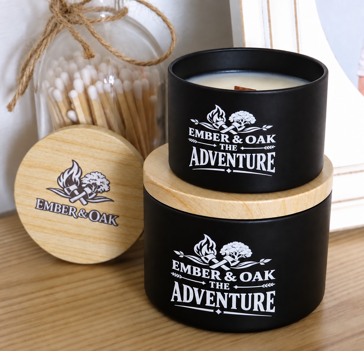 The Adventure luxury candle with wooden lid displayed alongside Ember & Oak packaging and accessories